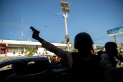 A police officer fires his weapon to disperse demonstrators during a protest to demand the resignation of Haitian President Jovenel Moise in Port-au-Prince, Haiti, Feb. 7, 2021.