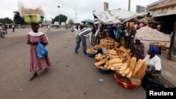Street vendors sell loaves of bread and other wares on a street in Bouake, Ivory Coast, December 2010.