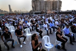 FILE - Relatives of victims killed in the massive blast last year at the Beirut port hold their portraits as they attend a Mass held to commemorate the first year anniversary of the tragedy, at the Beirut port, Lebanon, Aug. 4, 2021.