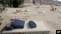 Fragments of a headstone are seen after it tumbled over onto a grave in the aftermath of an earthquake at Searles Valley Cemetery, in Trona, California, July 7, 2019.