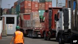FILE - In this photo taken Feb. 20, 2017, a customs agent observes the arrival of trucks with wood from the Peruvian Amazon at the port of Callao, Peru. 