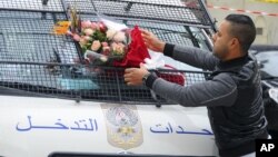 A man places a bouquet of flowers on a police van, near the bus that exploded in Tunis, Nov.25, 2015. 