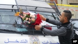 Un homme place un bouquet de fleurs devant une fourgonnette de la police près du lieu de l'attaque contre un bus de la garde de la sécurité présidentielle à Tunis, 25 novembre 2015. 