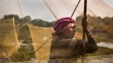 A Karbi tribal woman waits with her fishing net to participate in community fishing as part of Bhogali Bihu celebrations in Panbari village, some 50 kilometers (31 miles) east of Gauhati, India. &quot;Bhogali Bihu&quot; marks the end of the harvest season in the northeastern state of Assam.