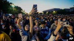 ARCHIVO - Varias personas toman fotografías con sus teléfonos en una calle cercana a la plaza de Tiananmén, el domingo 1 de octubre de 2023, en Beijing, China. 