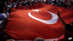 Protesters wave a large Turkish flag during an anti-coup rally in Taksim Square in Istanbul, July 25, 2016. 