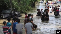 Warga berjalan mengarungi banjir di Tanggerang, Kamis, 2 Januari 2020. (Foto: Tatan Syuflana/AP)