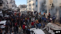 People gather as smoke rises from a UN school-turned-shelter after it was hit in an Israeli strike, in the Rimal neighborhood of Gaza City in the northern Gaza Strip on Nov. 14, 2024.