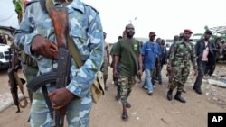 A man known as Commander Bauer, the chief of a group of pro-Ouattara fighters, walks with his men in northern Abidjan's Abobo district March 26, 2011