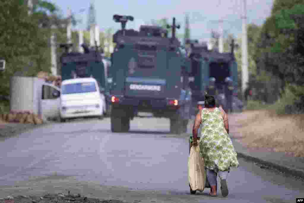 A woman walks near a French gendarmerie roadblock in Saint Louis on the way to Mont-Dore, in France&#39;s Pacific territory of New Caledonia. French officials on September 19 dealt with a new increase in violence in the country&#39;s overseas territories with security forces killing two men in New Caledonia and officials ordering a curfew after rioting in Martinique.