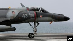 FILE - A French military plane lands on the French navy aircraft carrier Charles de Gaulle in the Persian Gulf.