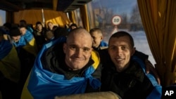 러시아에 잡혀있다 포로 교환으로 풀려난 우크라이나인들이 지난달 31일 버스 안에서 국기를 몸에 두르고 있다.