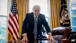 President Donald Trump poses for a portrait in the Oval Office in Washington, April 21, 2017.