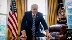 FILE - President Donald Trump poses for a portrait in the Oval Office in Washington, April 21, 2017.