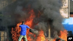 A young man throws a tire onto a fire during a protest by supporters of opposition leader Alassane Ouattara in Abidjan, 03 Dec 2010.