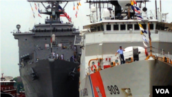 A U.S. coastguardsman on the deck of his cutter speaks to his family by mobile phone saying that he will be in port soon, New York City, May 23, 2014. (Adam Phillips/VOA)