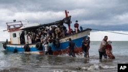 Local fisherman help ethnic-Rohingya people as they arrive on Lancok Beach, North Aceh, Indonesia, Thursday, June 25, 2020. Indonesian fishermen discovered dozens of the hungry, weak Rohingya Muslims on the wooden boat adrift off Indonesia's…