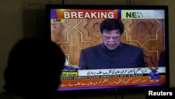 A man looks at a television screen displaying cricketer-turned-politician Imran Khan being sworn in as prime minister of Pakistan, in Karachi, Pakistan, Aug. 18, 2018.