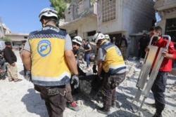 Members of the Syrian Civil Defense carry away a body retrieved from the rubble following a reported regime airstrike on the village of Kafriya, in Syria's Idlib province, July 13, 2019.