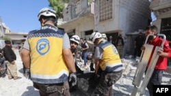 Members of the Syrian Civil Defense carry away a body retrieved from the rubble following a reported regime airstrike on the village of Kafriya, in Syria's Idlib province, July 13, 2019.