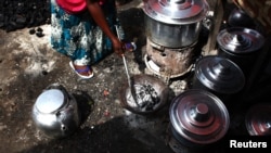 FILE - A woman adjusts the charcoal in a stove next to cooking pots at a village about 30 km (19 miles) south of South Sudan's capital Juba, June 21, 2013. 