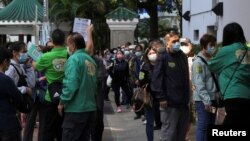 Orang-orang yang memakai masker berbaris di luar pusat vaksinasi komunitas untuk menerima dosis vaksin CoronaVac di Hong Kong, China, 2 Desember 2021. (Foto: REUTERS/Lam Yik)