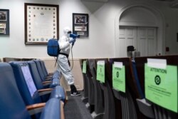 A member of the cleaning staff, dressed in a protective suit, sprays the James Brady Briefing Room of the White House, Oct. 5, 2020.