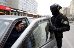 A police officer wearing a protective mask and glasses stops a car driver to check his documents in Grozny, Russia, March 30, 2020.