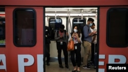 Passengers using their phones, wear masks to protect themselves from coronavirus in a Light Rail Transit train in Kuala Lumpur, Malaysia, Feb. 10, 2020.