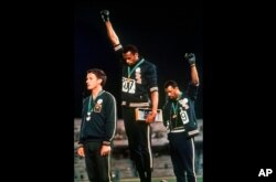FILE - In this Oct. 16, 1968 file photo, U.S. athletes Tommie Smith, center, and John Carlos raise their gloved fists after Smith received the gold and Carlos the bronze for the 200 meter run at the Summer Olympic Games in Mexico City.
