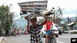 A boy carries metal sheets that were blown away from houses in the winds of Typhoon Goni in Albay province, central Philippines on Nov. 3, 2020.