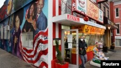 Seorang pelanggan mengenakan masker, keluar dari restoran Ben's Chili Bowl, di tengah pandemi Covid-19 di Washington, D.C., 30 April 2020. (REUTERS/Jonathan Ernst).