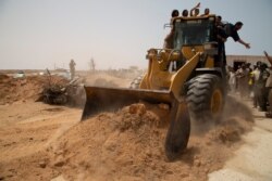 A bulldozer pushes earth to during a ceremony to reopen the road between the Libya cities of Misrata and Sirte, June 20, 2021. It was later reported closed.