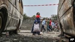 Residents walk by charred vehicles in Goma, Democratic Republic of the Congo, Jan. 31, 2025.