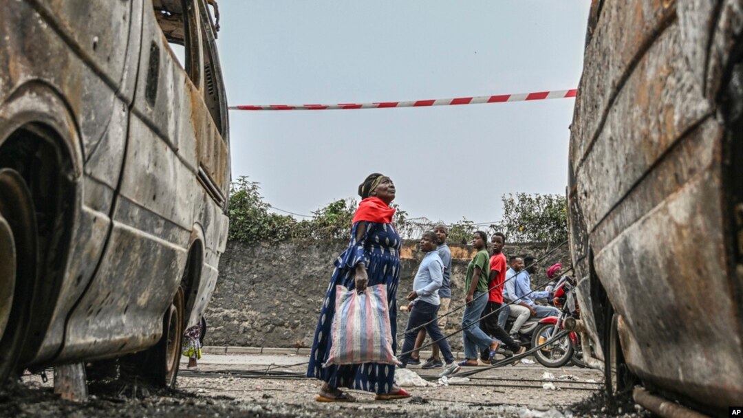 Moradores caminham perto de veículos carbonizados em Goma, República Democrática do Congo, a 31 de janeiro de 2025.