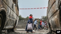 Moradores caminham perto de veículos carbonizados em Goma, República Democrática do Congo, a 31 de janeiro de 2025.