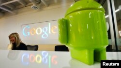 FILE - Google Android figurine sits on the welcome desk as employee Tracy McNeilly smiles at the new Google office in Toronto. 