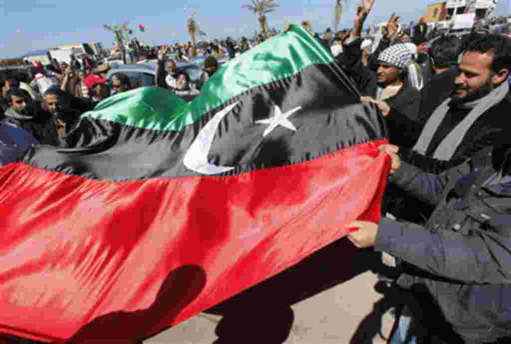 Manifestantes anti-Gadhafi levantan la antigua bandera de Libia para celebrar la libertad de la ciudad de Bengasi.