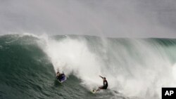 FILE - A surfer watches as a body board rider drops in on his wave at the "Bommie," a famous surfing spot near Sydney's Manly Beach.