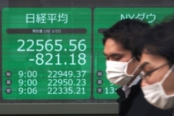 Men walk past an electronic stock board showing Japan's Nikkei 225 index at a securities firm in Tokyo, Feb. 25, 2020.