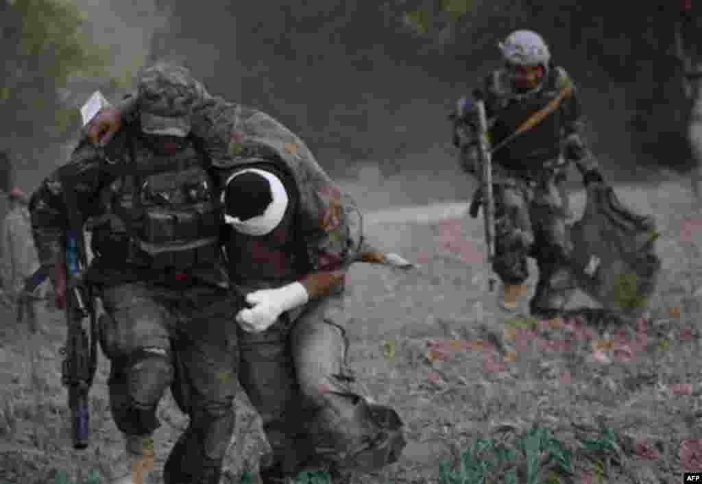 An Afghan National Army soldier carries his wounded colleague to a medevac helicopter from the U.S. Army's Task Force Lift "Dust Off", Charlie Company 1-52, following a roadside bomb attack on the outskirts of Kandahar, Afghanistan, Friday, July 29, 2011.