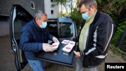 Relawan Turki Goecen Muelayim (kiri) dan Ural Hasan, dari layanan pengiriman makanan "Iftar To Go" di masjid Ditib, Wuppertal, jerman, menyiapkan pengiriman makanan mereka untuk lansia Muslim dan non-Muslim yang membutuhkan selama Ramadan di tengah pandemi COVID-19. (Foto: dok) 