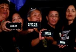 FILE - Journalists, including Rappler CEO Maria Ressa, raise their smartphones with words "STOP THE ATTACKS!" in a rally for press freedom in Quezon City, Philippines, Feb. 15, 2019.