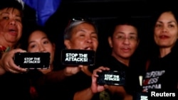 FILE - Journalists, including Rappler CEO Maria Ressa, raise their smart phones with words "STOP THE ATTACKS!" in a rally for press freedom in Quezon City, Philippines, Feb. 15, 2019. 