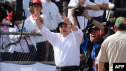 El presidente nicaragüense, Daniel Ortega (C), muestra el signo V mientras saluda a sus simpatizantes durante la conmemoración del 40 aniversario de la Revolución Sandinista en la plaza "La Fe" en Managua.