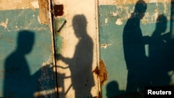 FILE - The shadows of vendors preparing dishes for a nightly food market are cast on a wall at the waterfront of Zanzibar Town in Zanzibar, Nov. 22, 2007. 