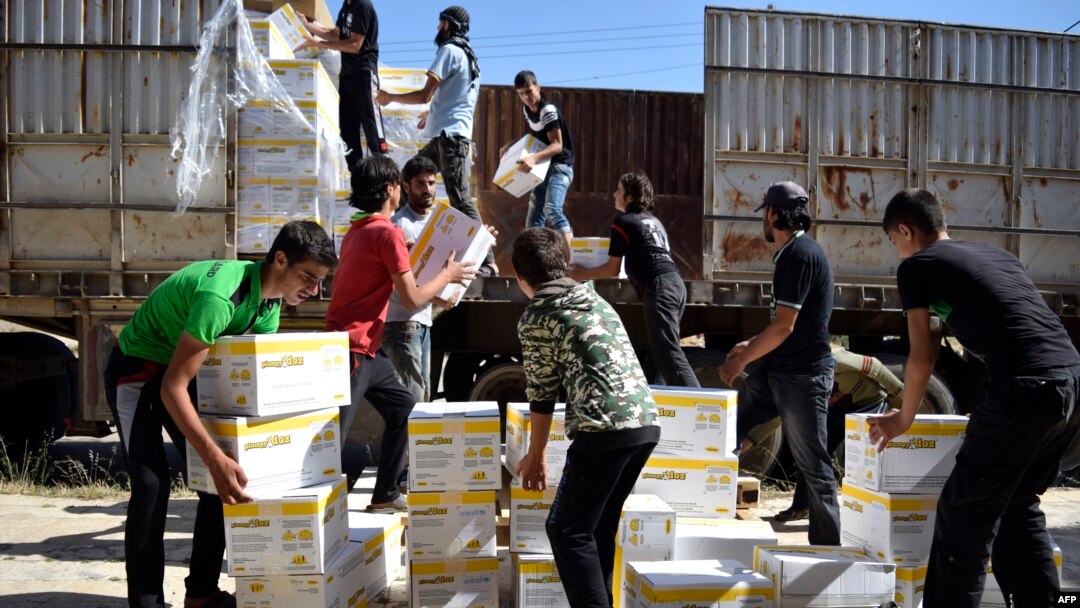 Pria-pria Suriah mengangkut kotak-kotak berisia bantuan dari Program Pangan Dunia PBB (WFP) di di al-Houla, pinggiran kota Homs sebelah utara, Suriah tengah (25/5). (AFP/Mahmoud Taha)