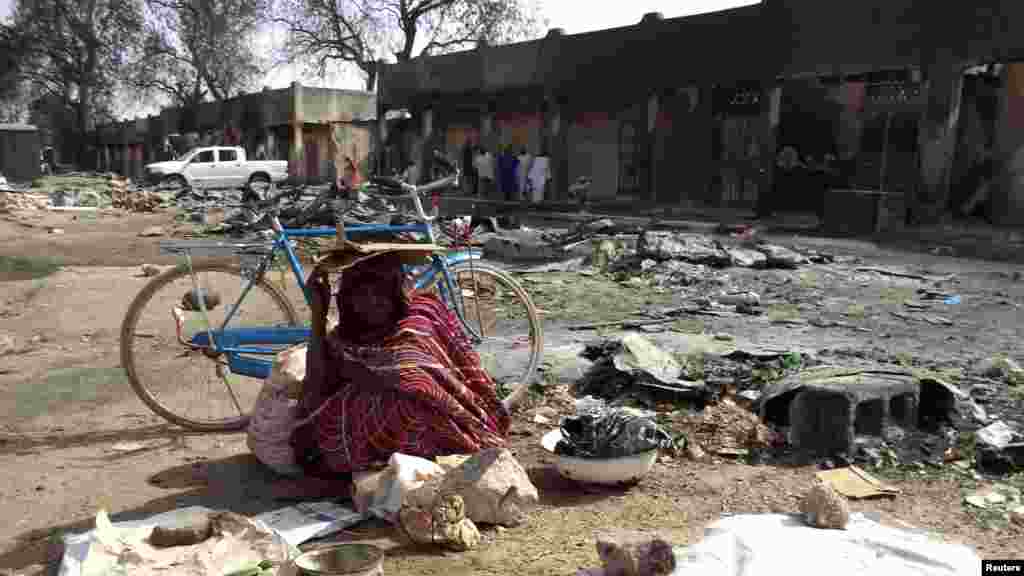 A woman sits amongst the ruins of the burnt Bama Market, which was destroyed by gunmen in last Thursday's attack, in Maiduguri, northeast Nigeria April 29, 2013.