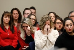 FILE - Victims and others look on as Rachael Denhollander speaks at the sentencing hearing for Larry Nassar, a former team USA Gymnastics doctor who pleaded guilty in November 2017 to sexual assault charges, in Lansing, Mich., Jan. 24, 2018.