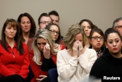 FILE - Victims and others look on as Rachael Denhollander speaks at the sentencing hearing for Larry Nassar, a former team USA Gymnastics doctor who pleaded guilty in November 2017 to sexual assault charges, in Lansing, Mich., Jan. 24, 2018.